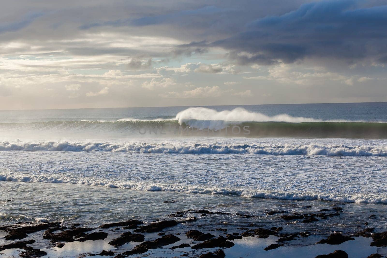 Ocean Waves crashing water power along beach rocky coastline from storm weather.