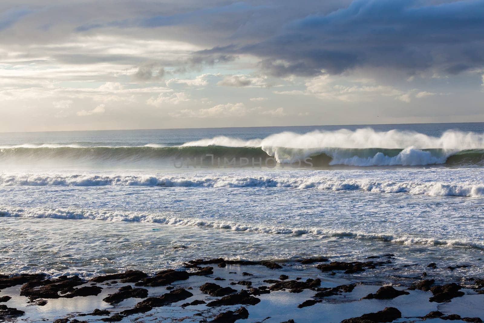 Ocean Waves crashing water power along beach rocky coastline from storm weather.