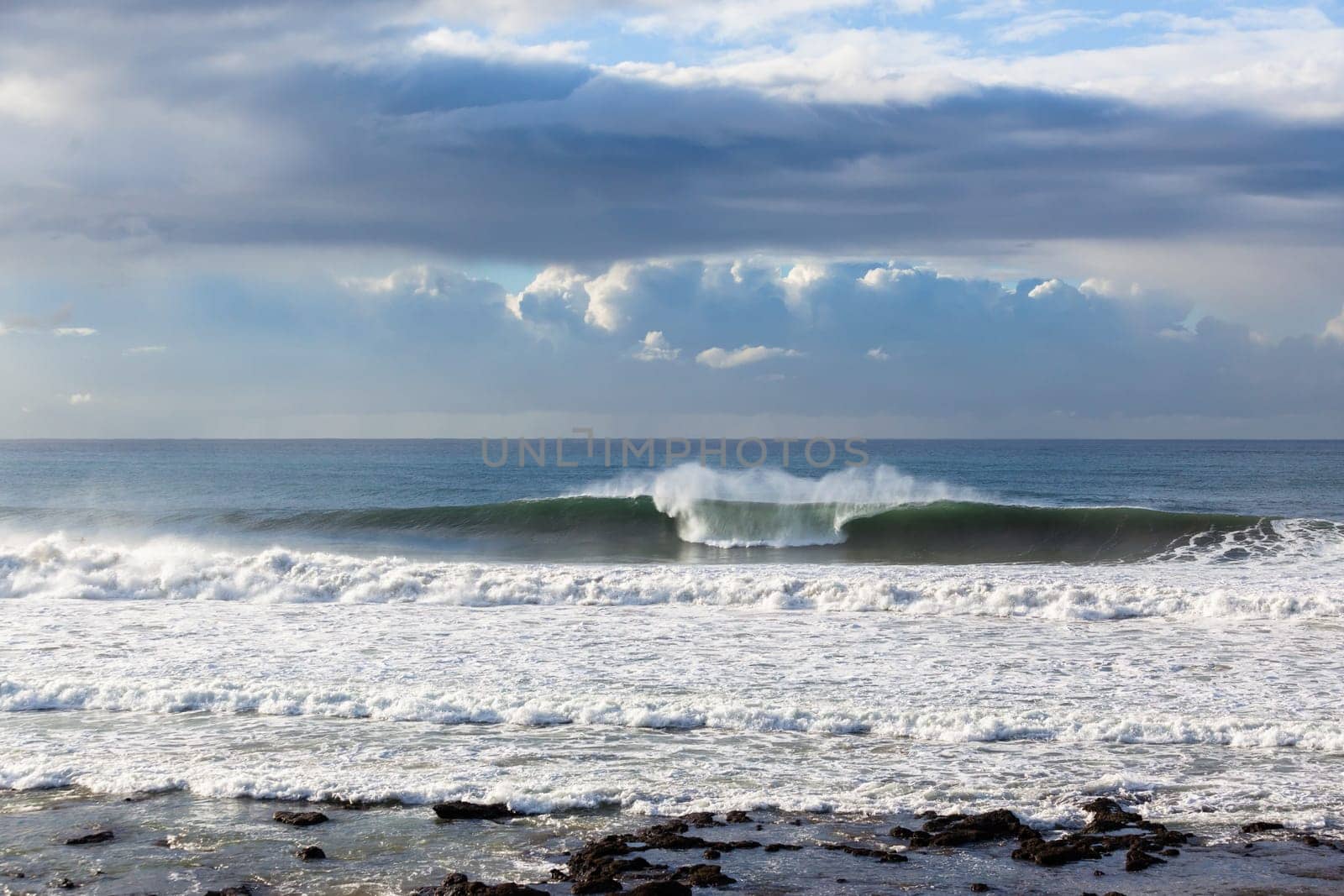 Ocean Waves crashing water power along beach rocky coastline from storm weather.