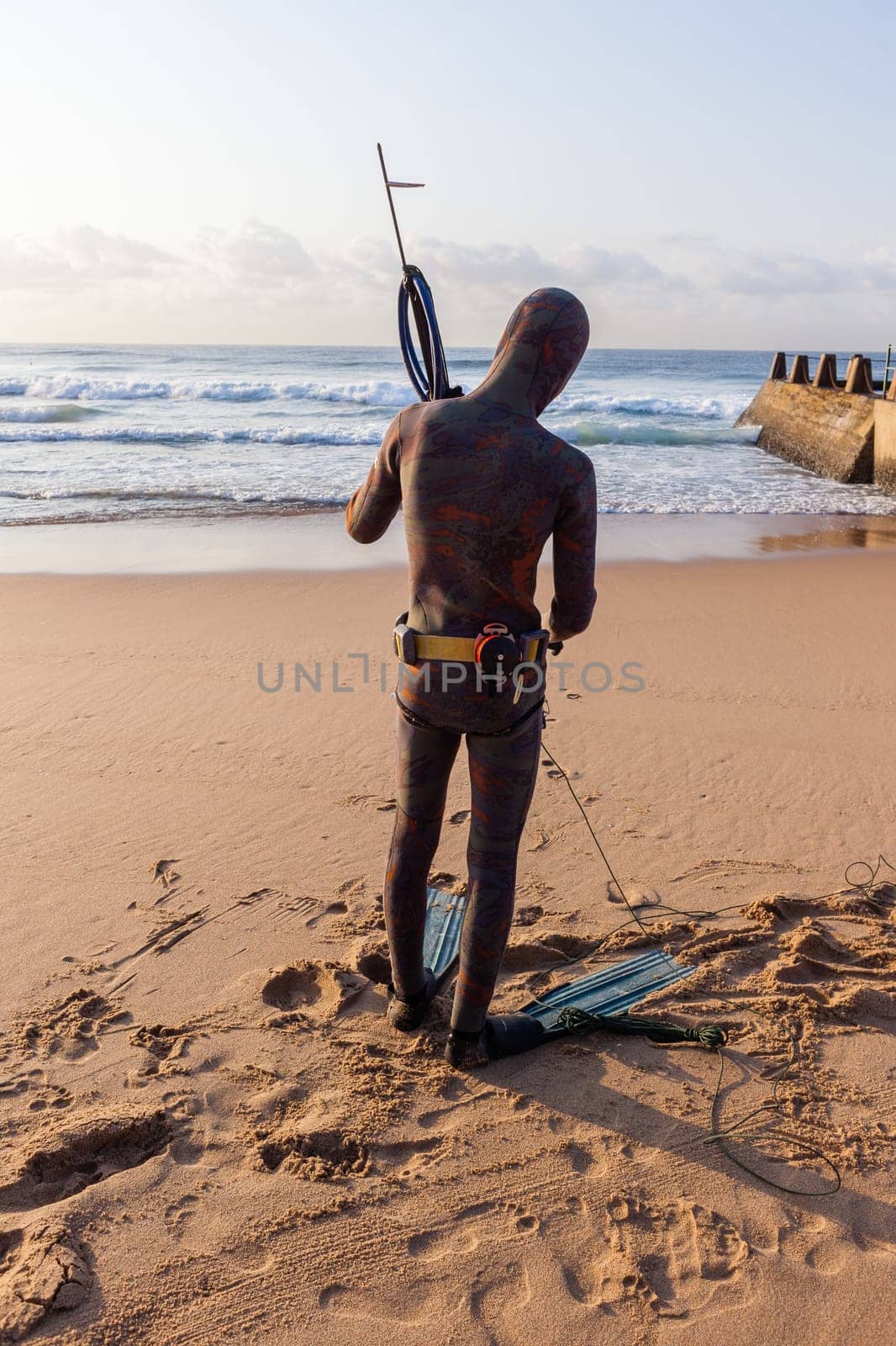 Spearfishing unidentified diver on beach about to enter blue ocean sea waters swimming sporting lifestyle