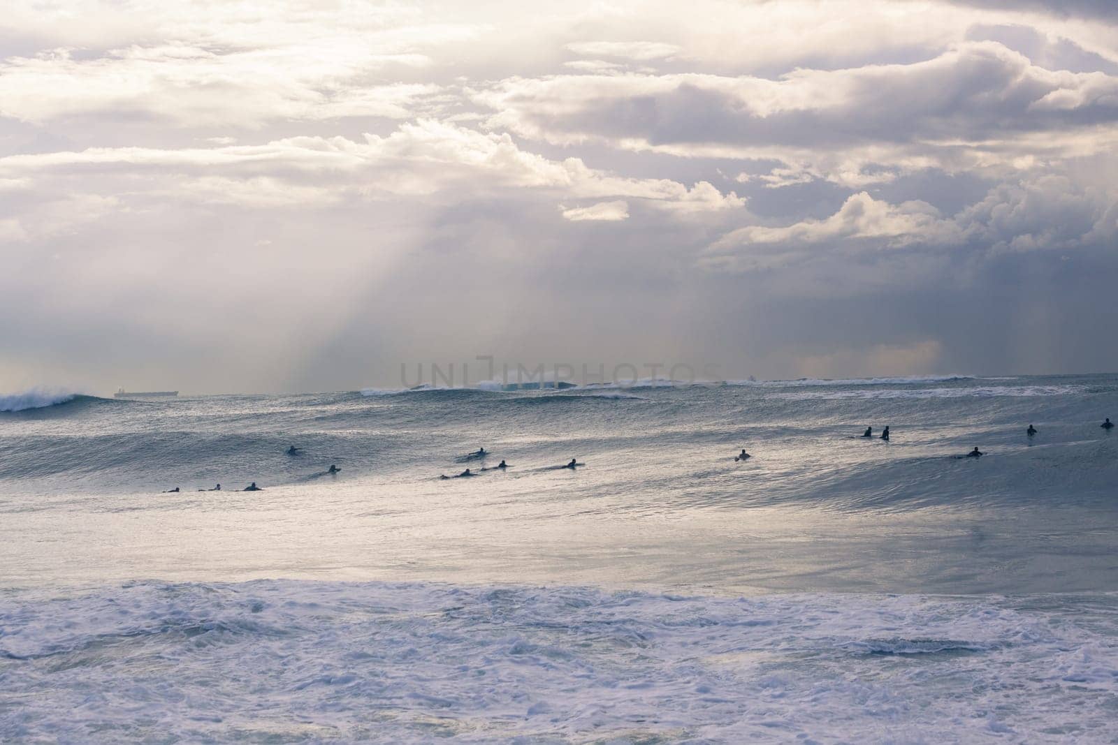 Surfers surfing out in large ocean storm waves.