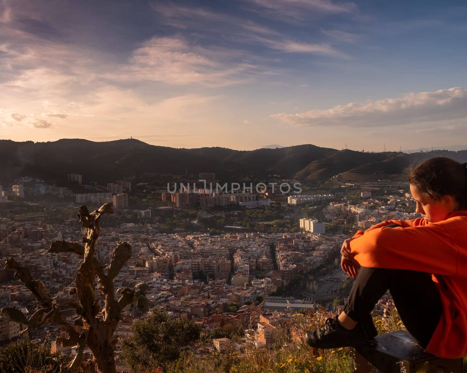 Sad girl sitting on the hill embracing her knees and looking away at sunset, sadly depressed teenager spending time alone, thoughtful young girl feeling lonely or frustrated thinking about problems