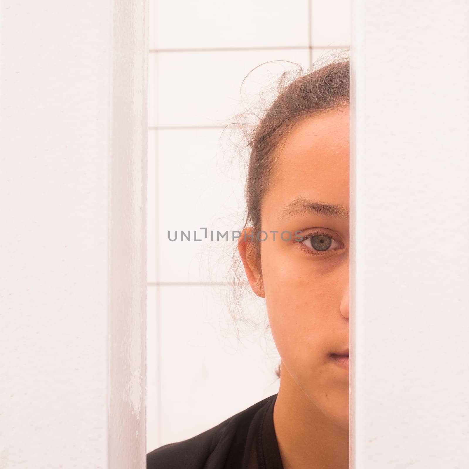 Close up half face portrait teenager girl looking through white metal bars, self-awareness and self worth concept, square image
