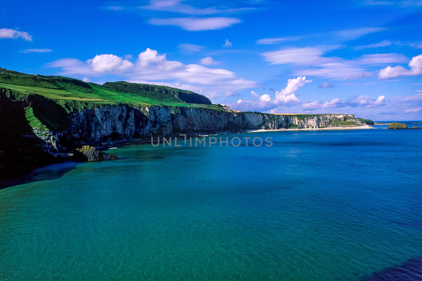 Landscape of Northern Ireland, coastline and cliff, green hills and blue sky along Causeway Coastal Route, County Antrim, United Kingdom