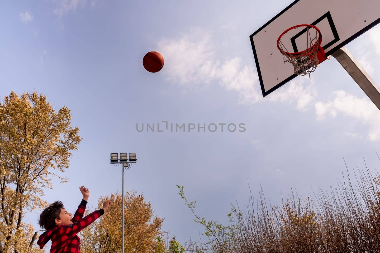 Body part of dynamic young boy with arms raised shooting a basket ball, horizontal composition, copy space