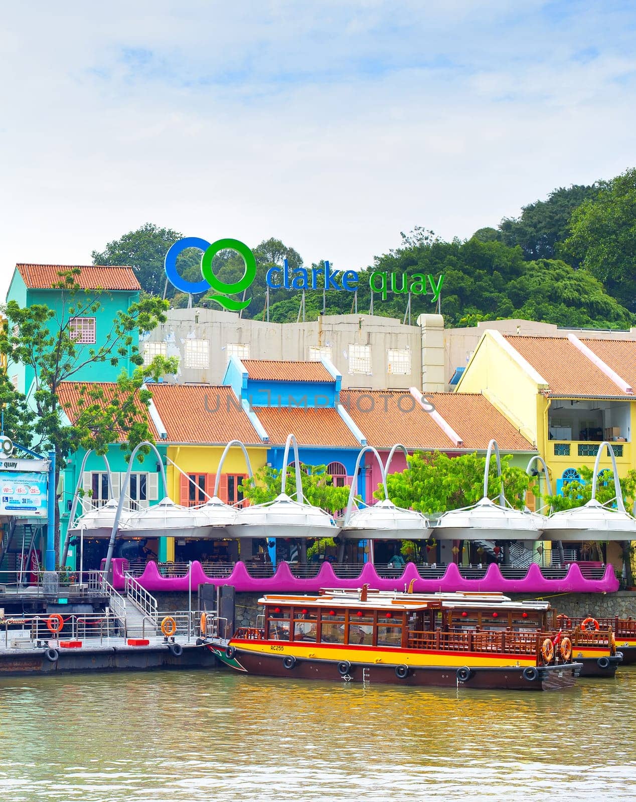 SINGAPORE - FEBRUARY 15, 2017: Colorful houses of Clarke Quay district by the river with traditional boats