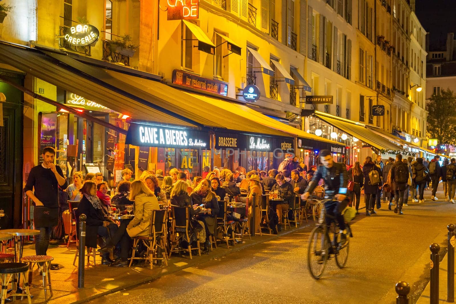 PARIS, FRANCE - NOVEMBER 09, 2018: People at a street restaurant in Paris at night. Paris is the most visited city in Europe