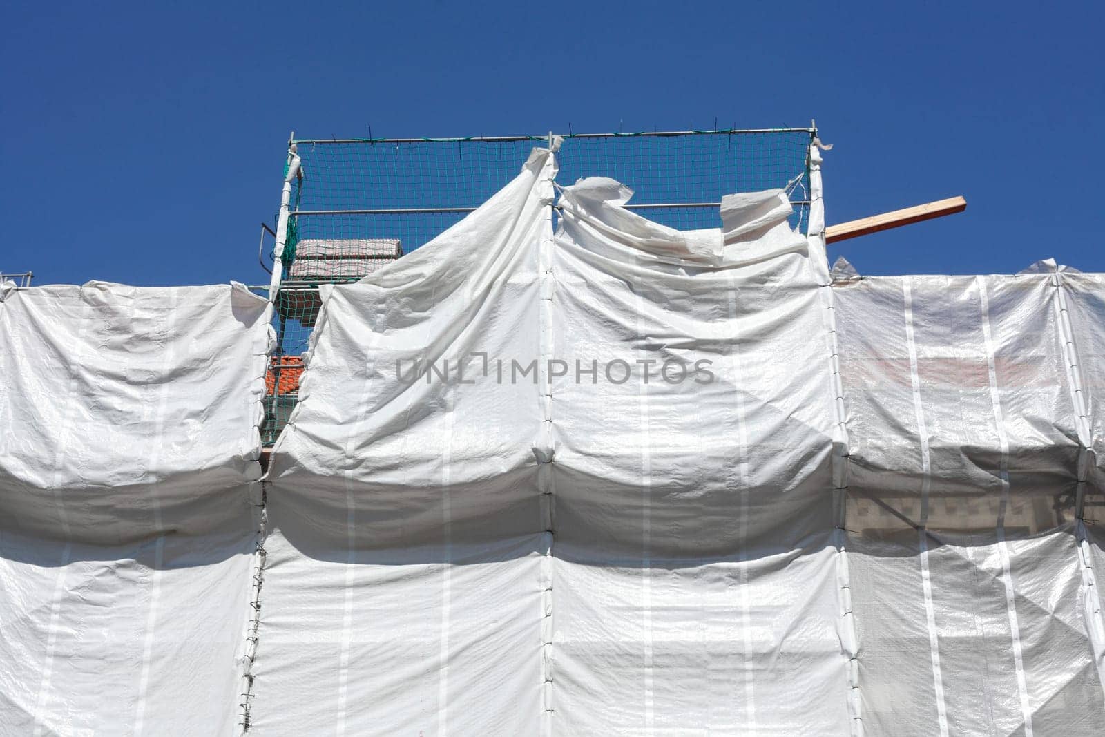 Covered facade of a historic building, renovation, tarpaulin, construction site, scaffolding, house facade