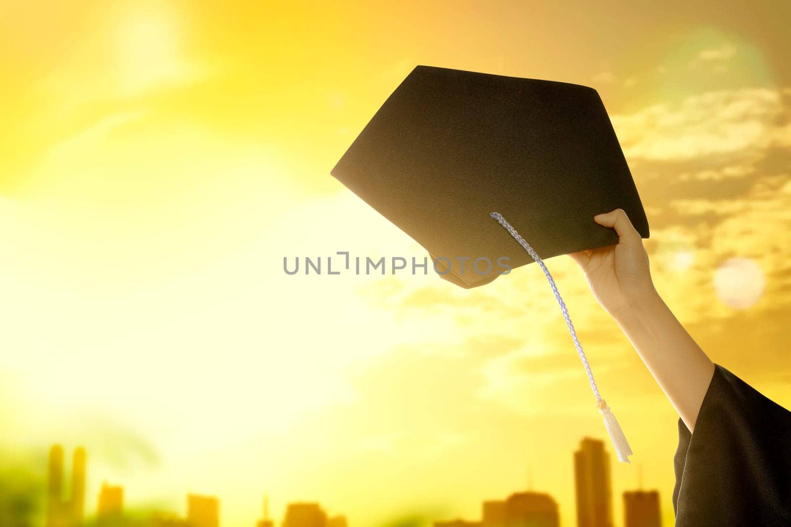 Hand holding graduation hat with sunlight background. Graduation concept