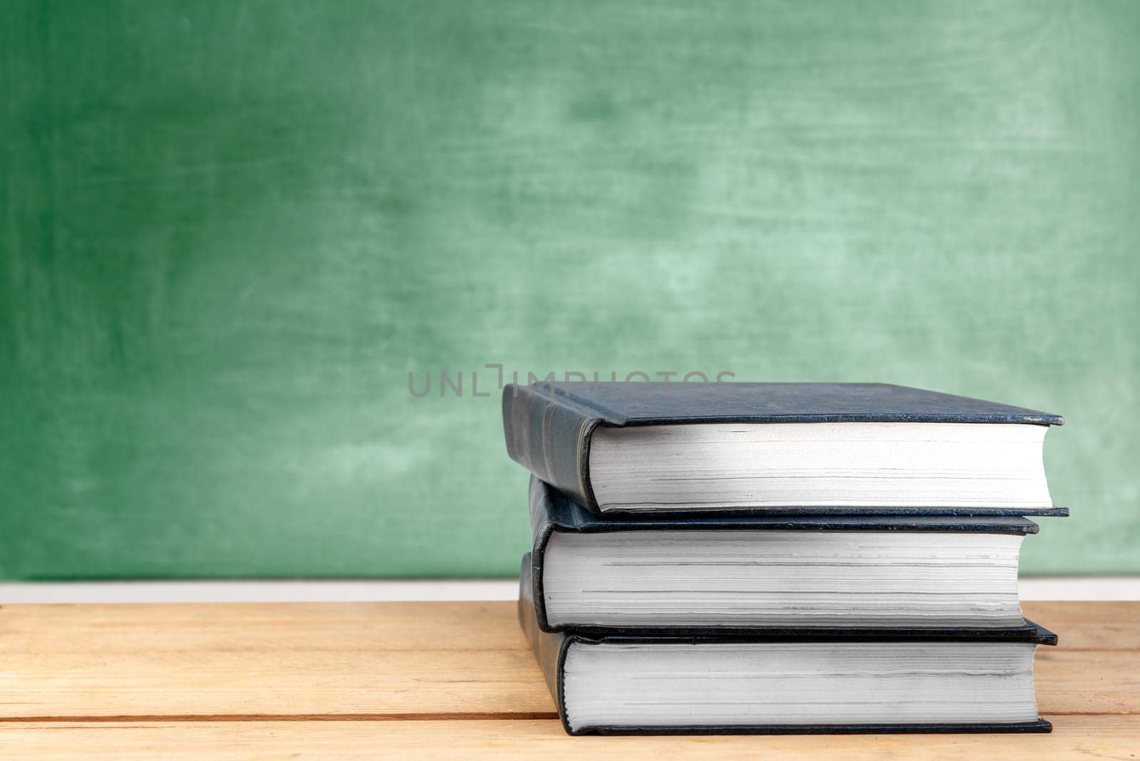 Pile of books on wooden table with chalkboard background. Back to School concept