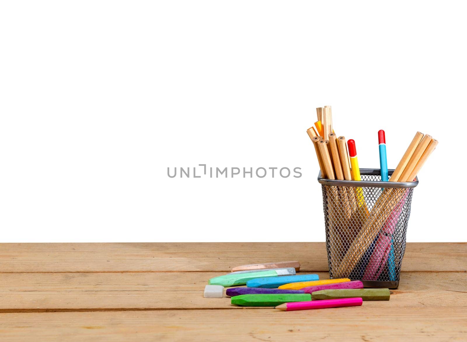 Pencils in basket container and colorful crayons on wooden table isolated over white background. Back to School concept