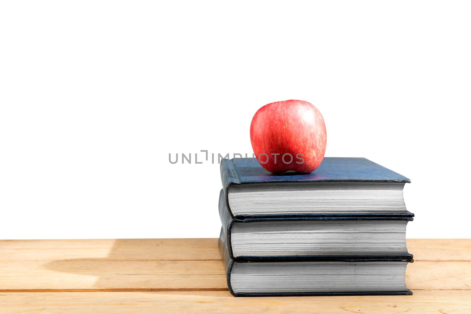 Pile of books with apple on wooden table isolated over white background. Back to School concept