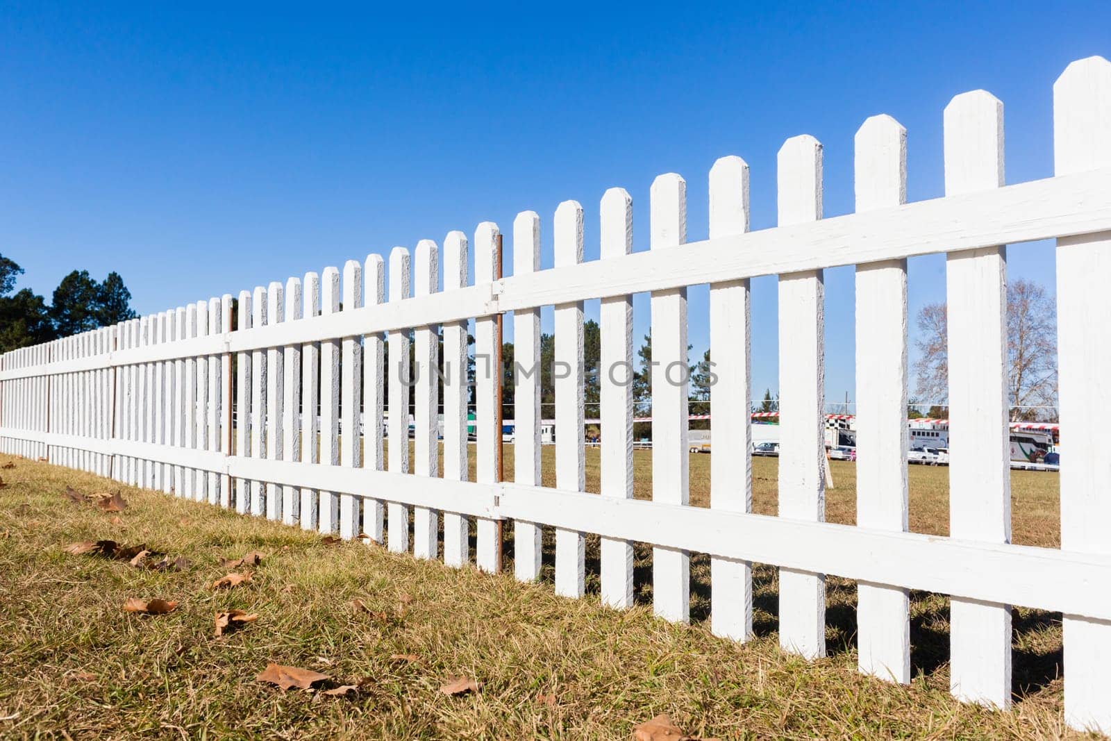 Boundary three feet wood white fence boundary across grass field blue sky day