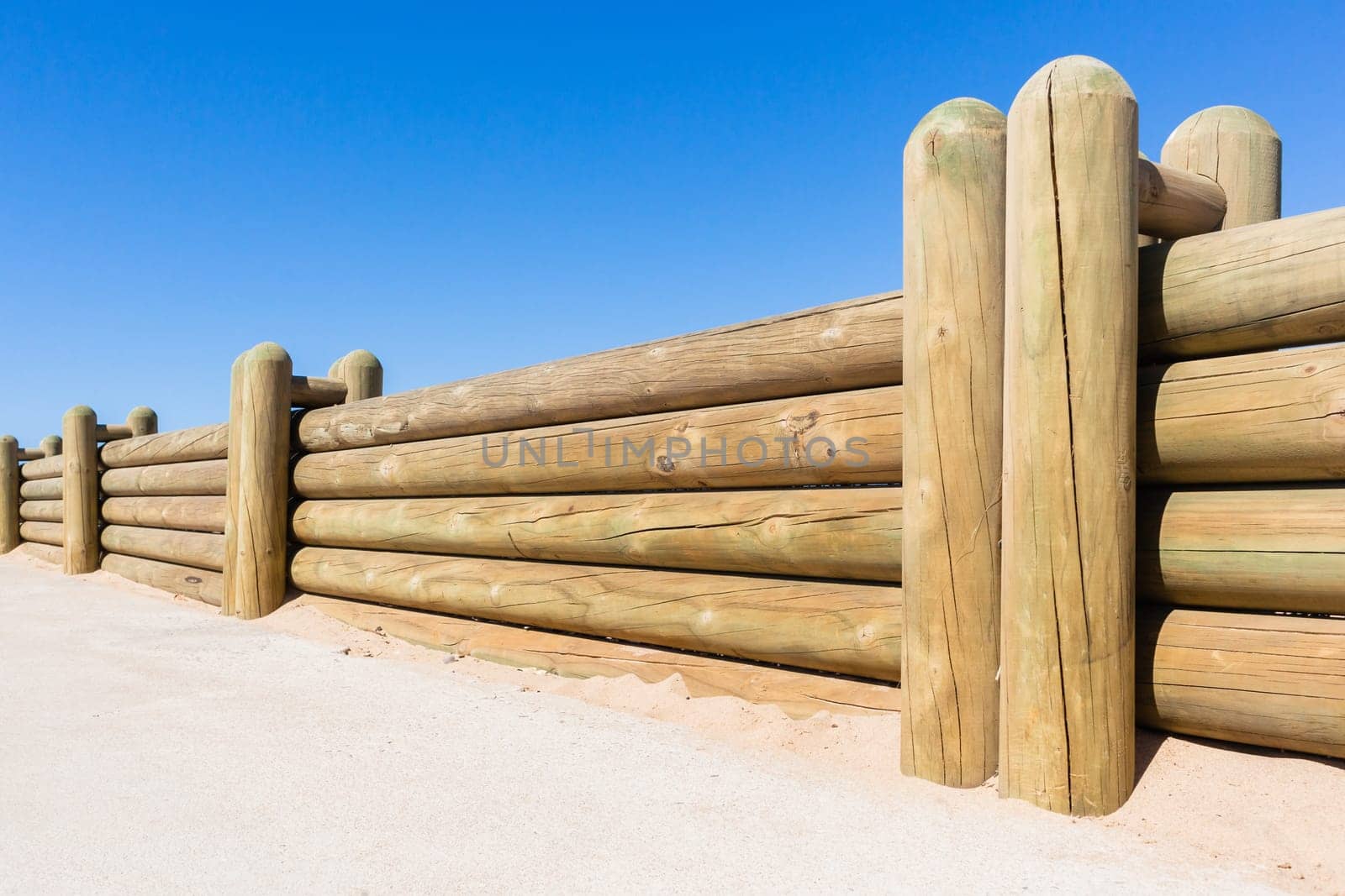 Wood poles low boundary fence wall decor outdoors closeup photo against blue sky