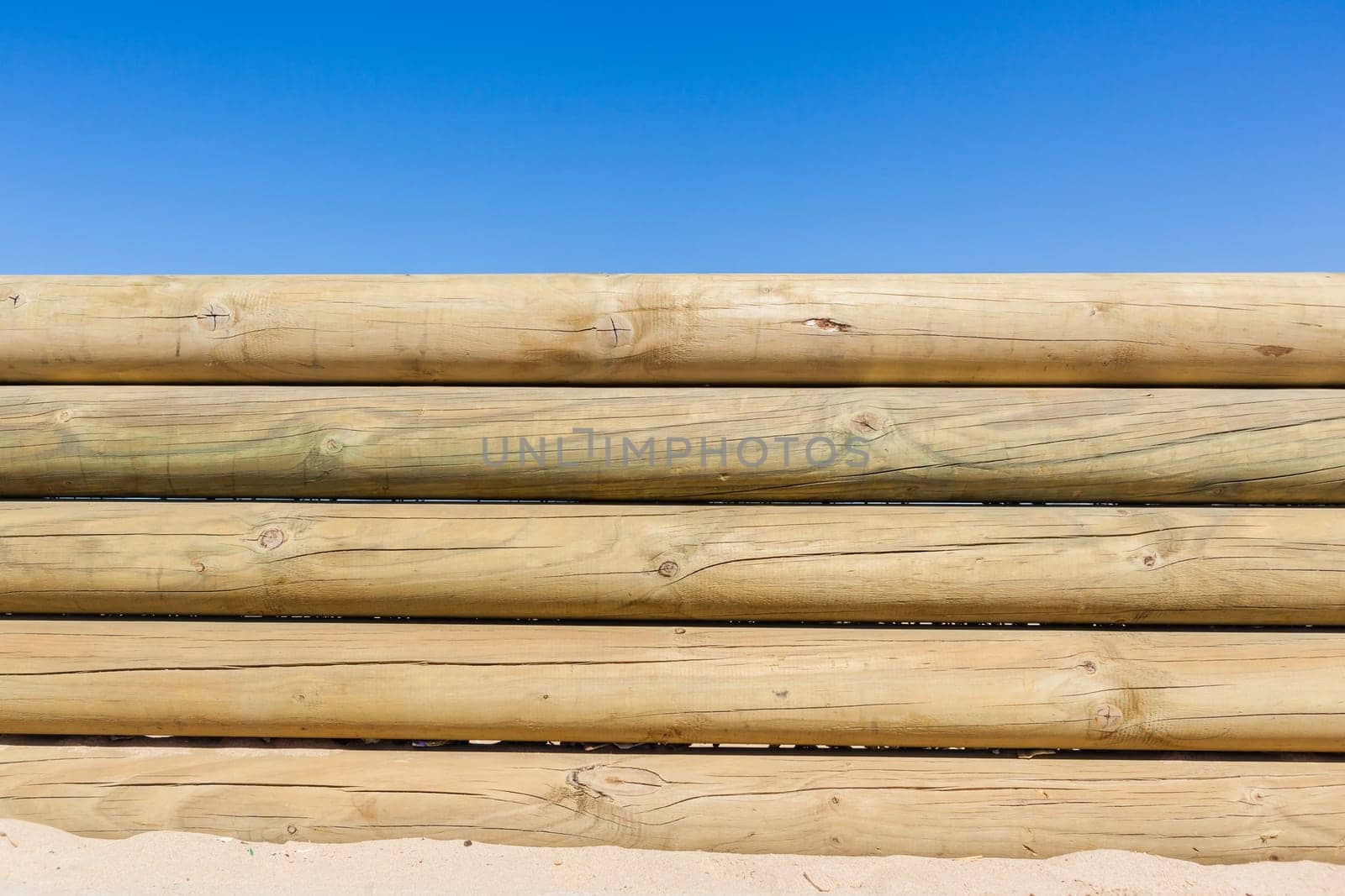 Wood poles low boundary fence wall decor outdoors closeup photo against blue sky