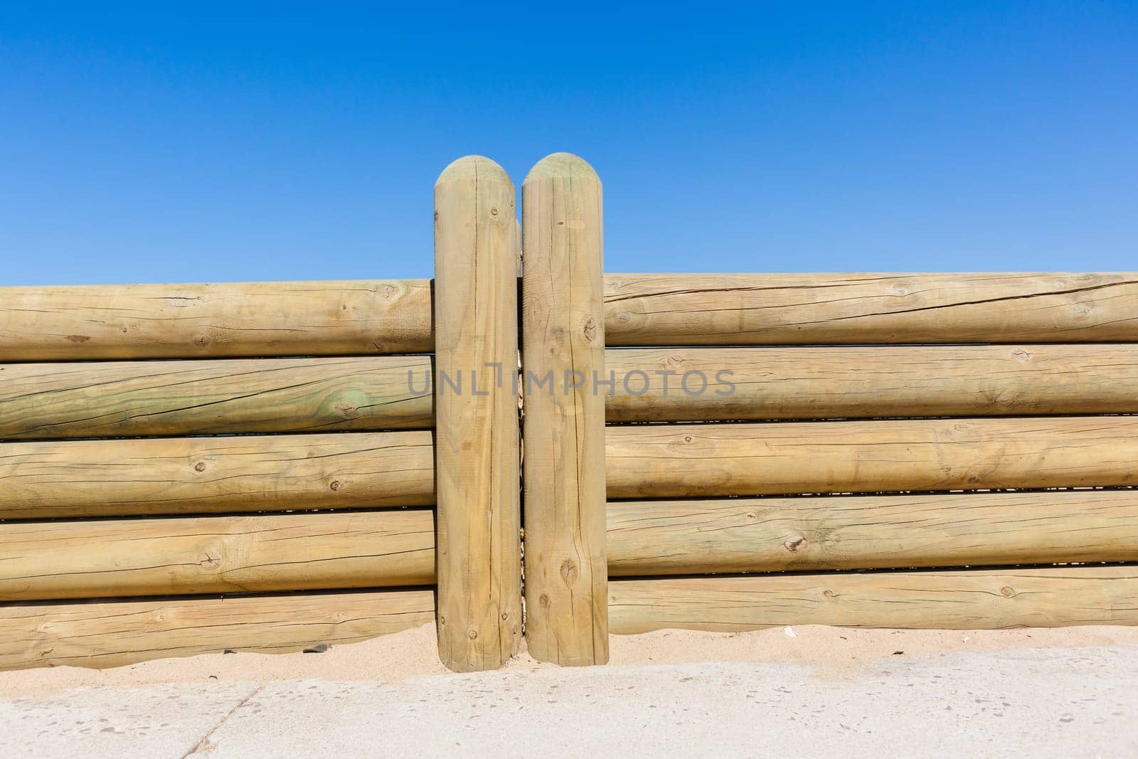 Wood poles low boundary fence wall decor outdoors closeup photo against blue sky