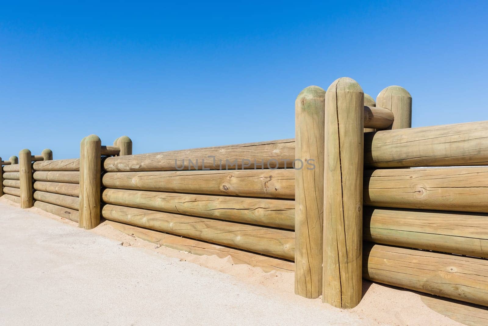 Wood poles low boundary fence wall decor outdoors closeup photo against blue sky