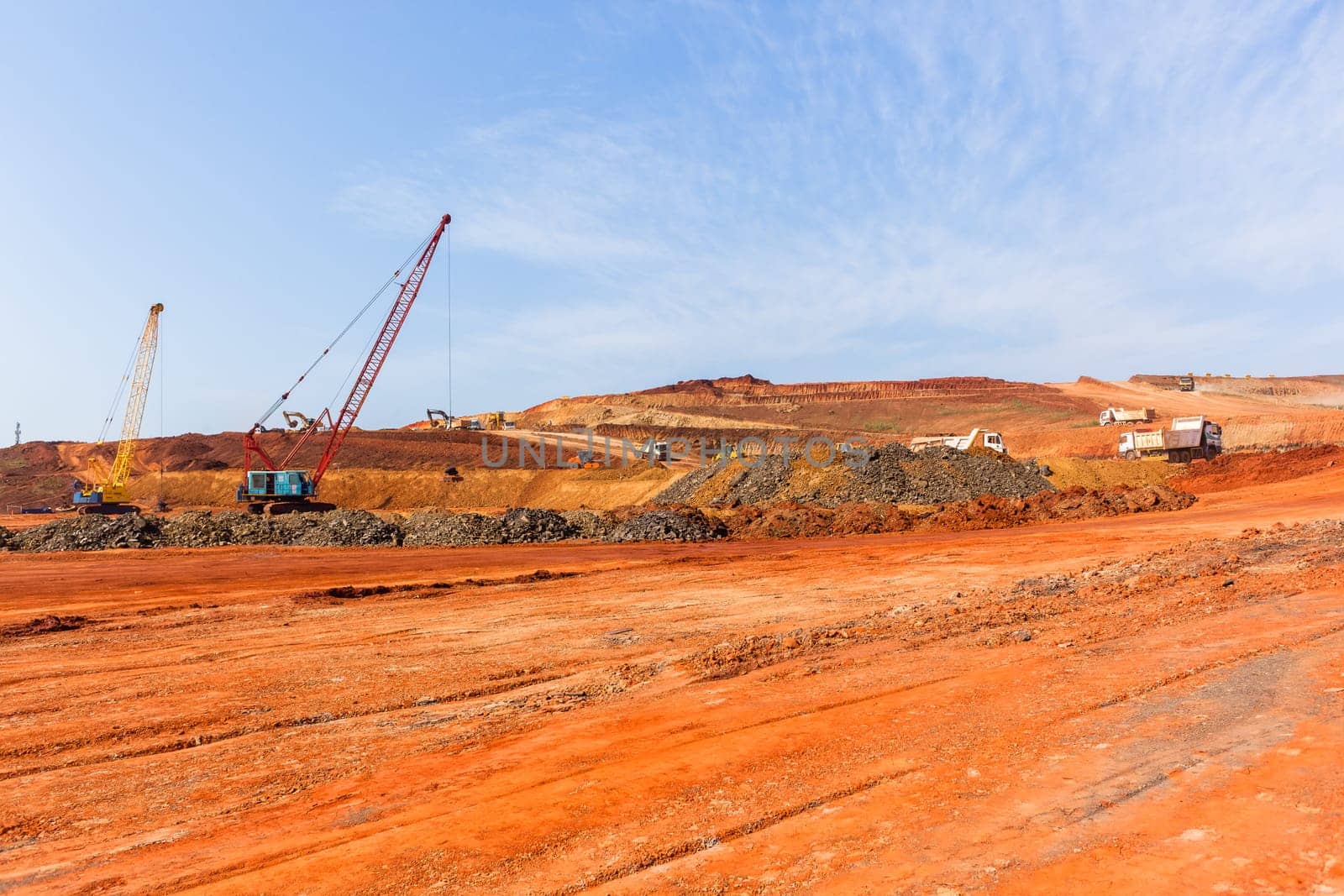 Industrial construction site overlooking large project expansion with graders,excavators,cranes machines into countryside sugarcane fields expanding earthworks infrastructure.