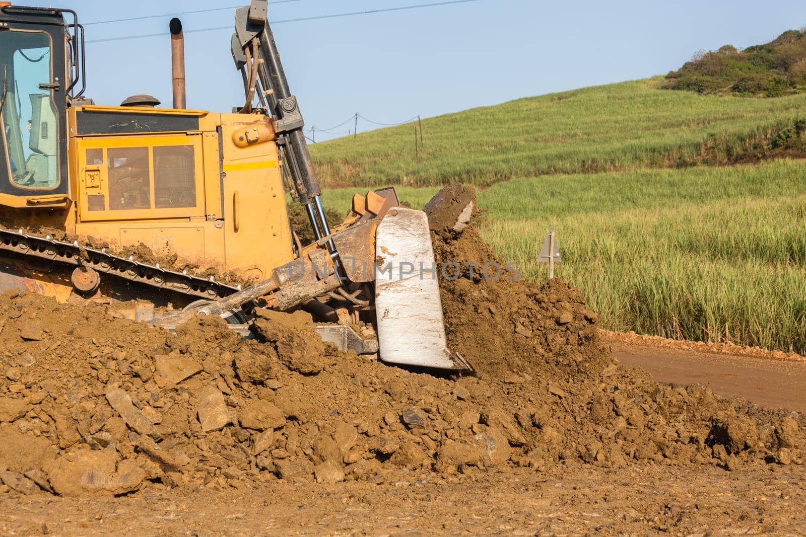 Construction industrial earthworks landfill dozer machine scoop bucket moving sand stones closeup abstract.