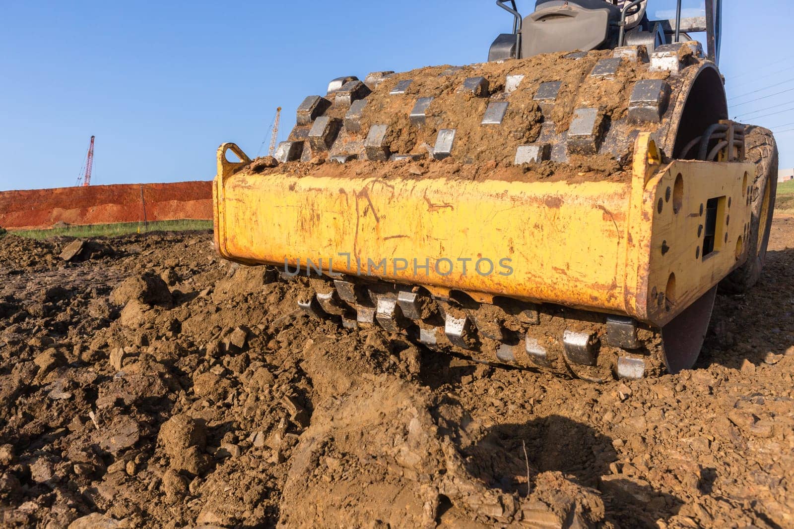 Construction industrial earthworks landfill compactor machine vibration leveling sand stones closeup abstract.