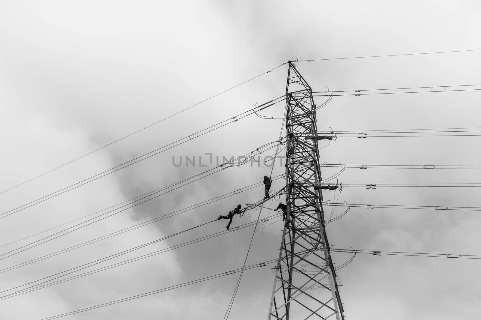 Electricians high rigging working maintnance on electrical cable power lines on steel tower structure.