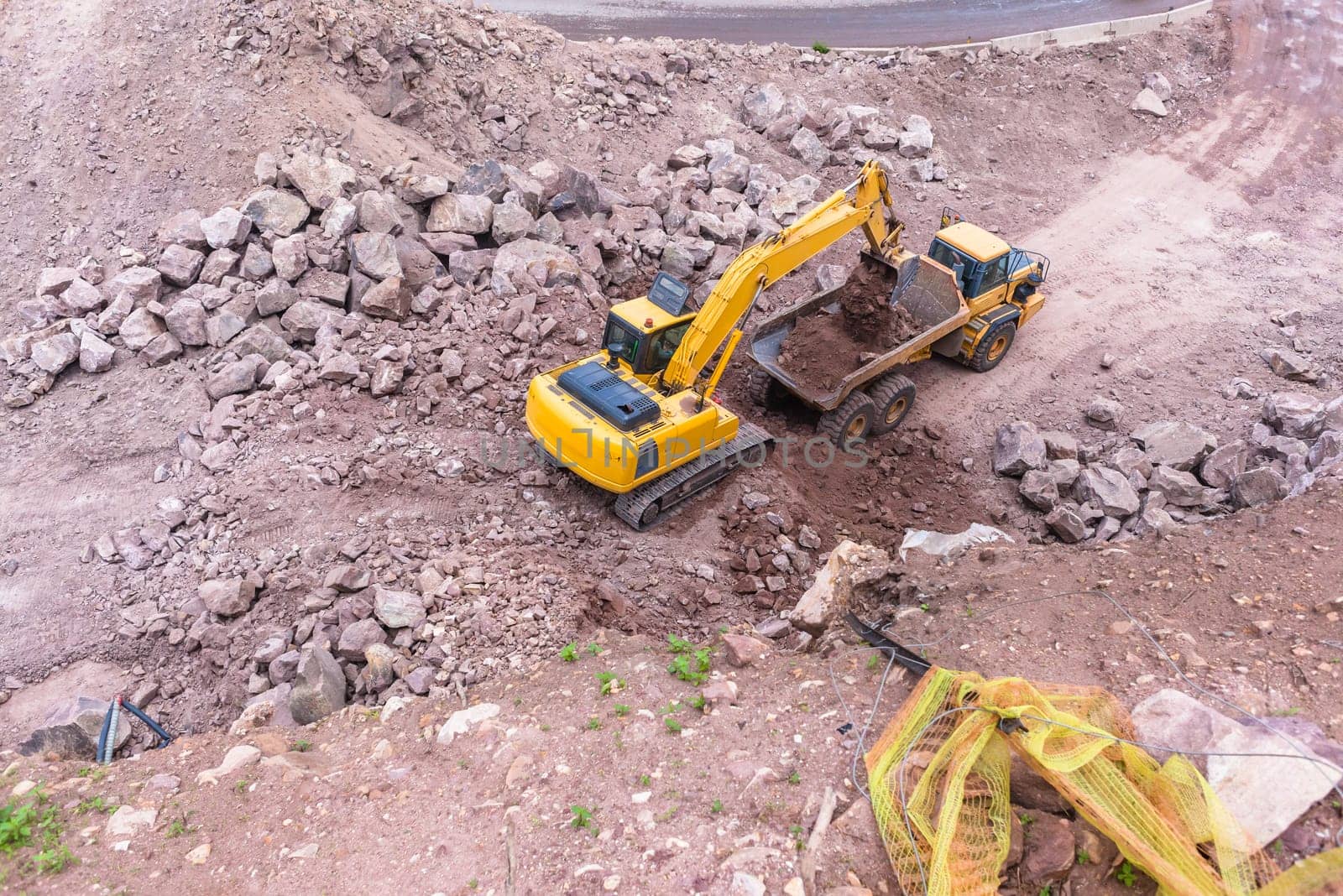 Industrial excavator machine loading construction truck vehicle heavy rock earthworks.
