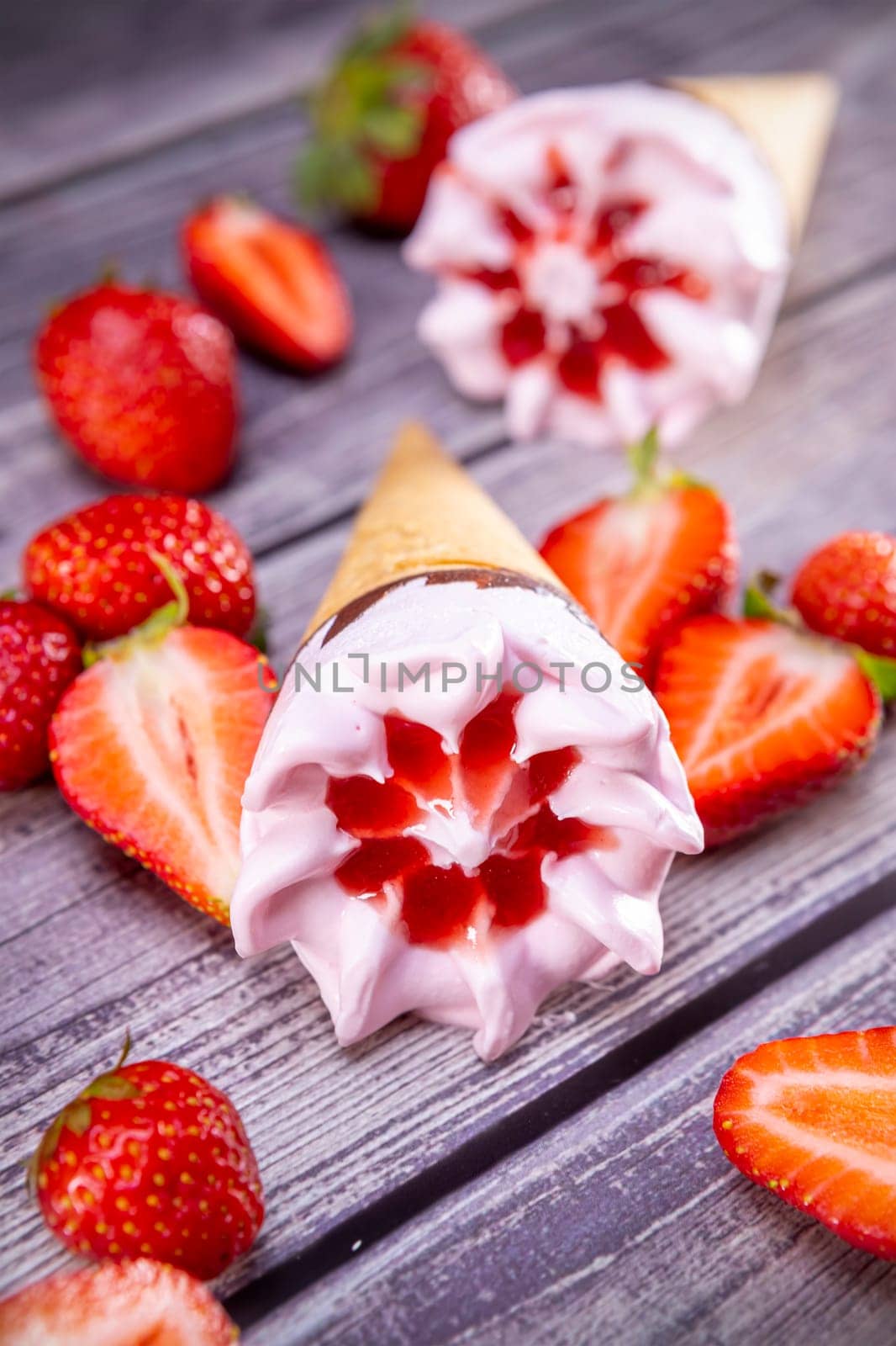 Ice cream cones with strawberries on a vintage wooden table summer. Focus on ice cream.