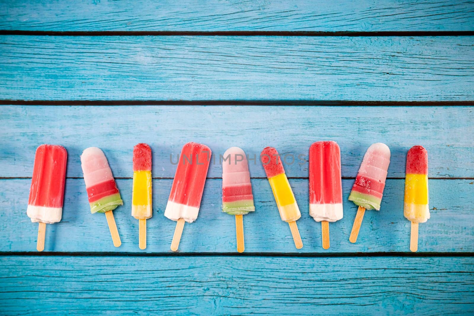 Colorful fruit ice cream stick look fresh to eat placed on a blue vintage wooden floor