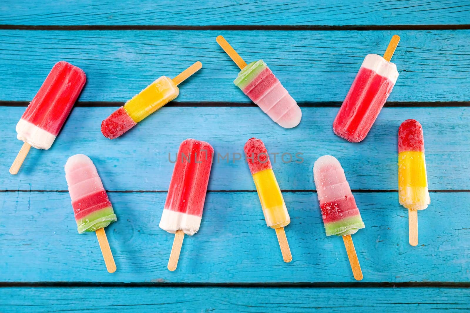 Colorful fruit ice cream stick look fresh to eat placed on a blue vintage wooden.