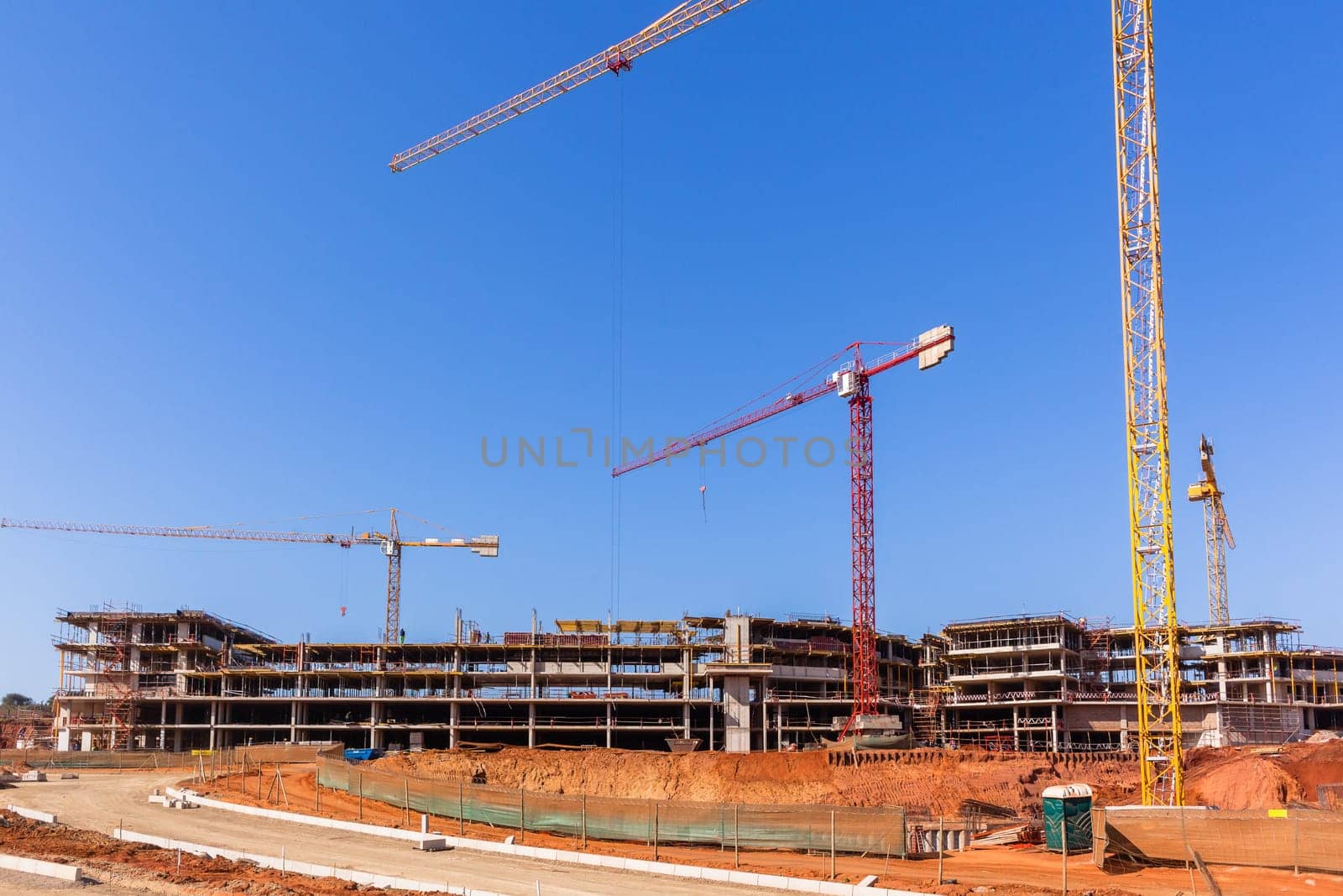 Building construction site industrial cranes concrete levels earthworks halfway apartment housing project.