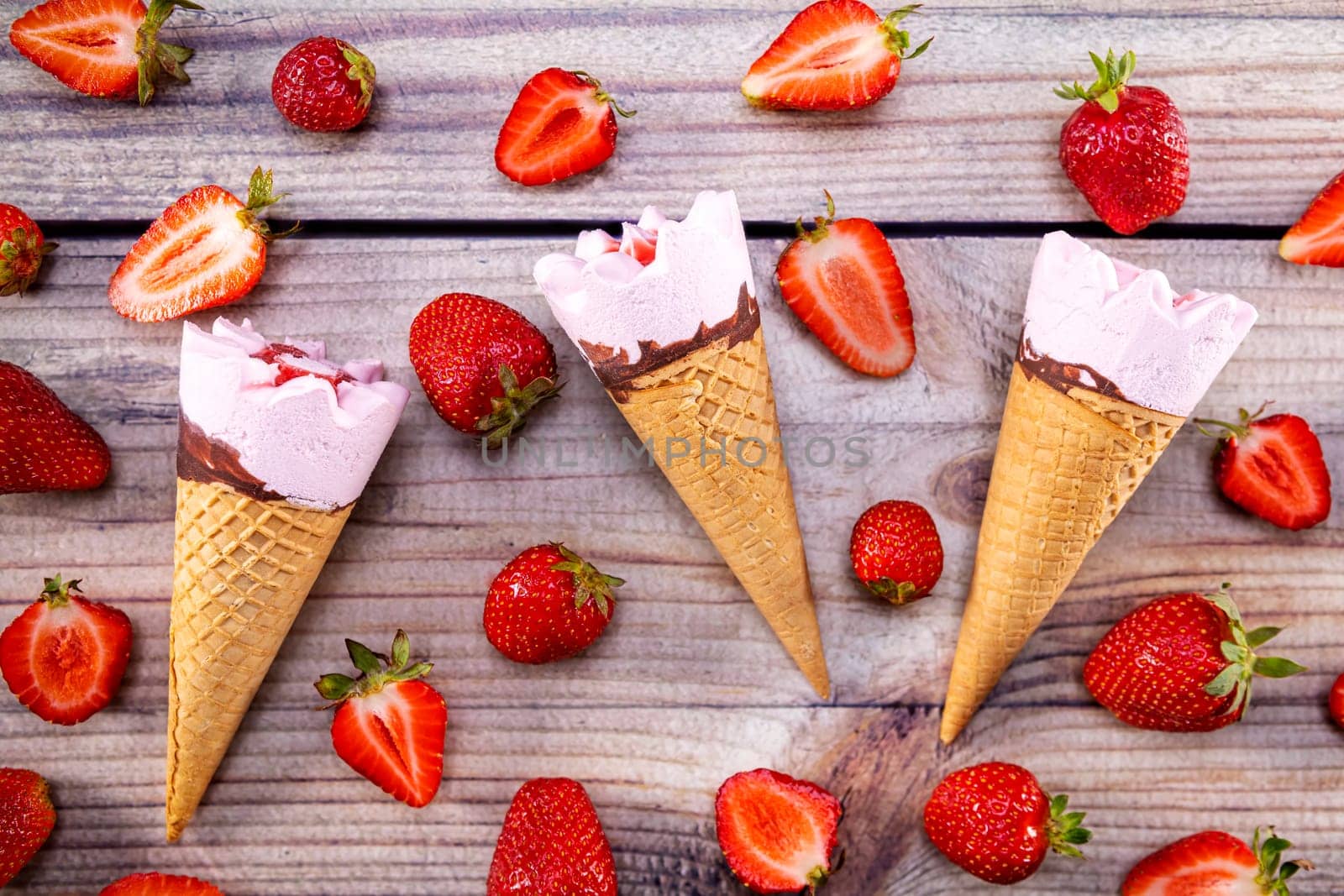 Ice cream cones with strawberries on a vintage wooden table summer. Focus on ice cream.