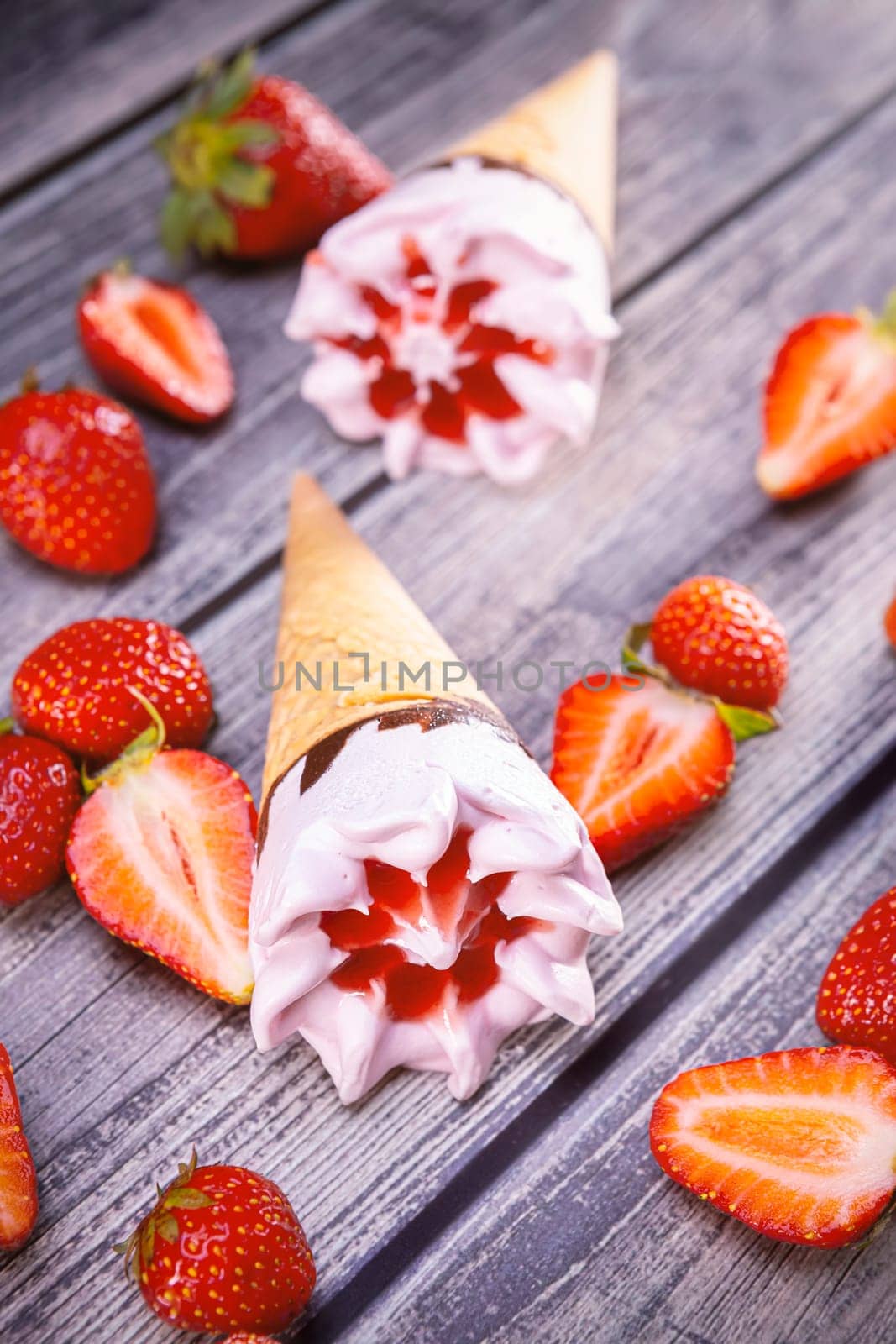 Ice cream cones with strawberries on a vintage wooden table summer. Focus on ice cream.