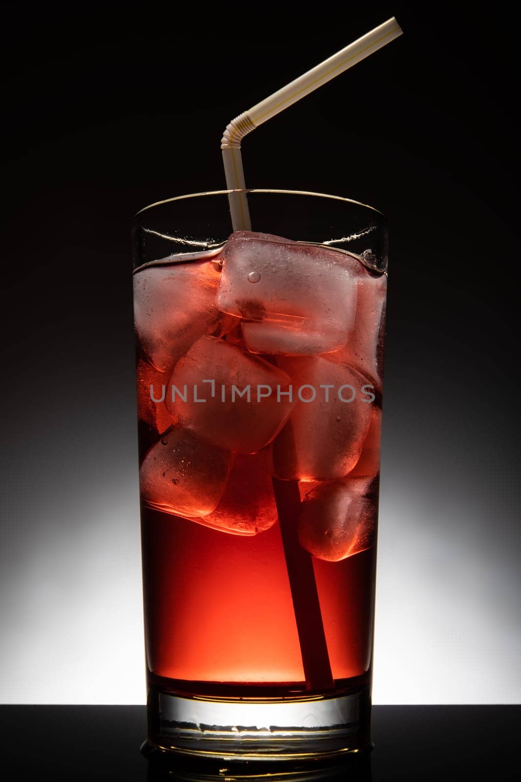 Isolated glass with a red cocktail and ice-cubes.