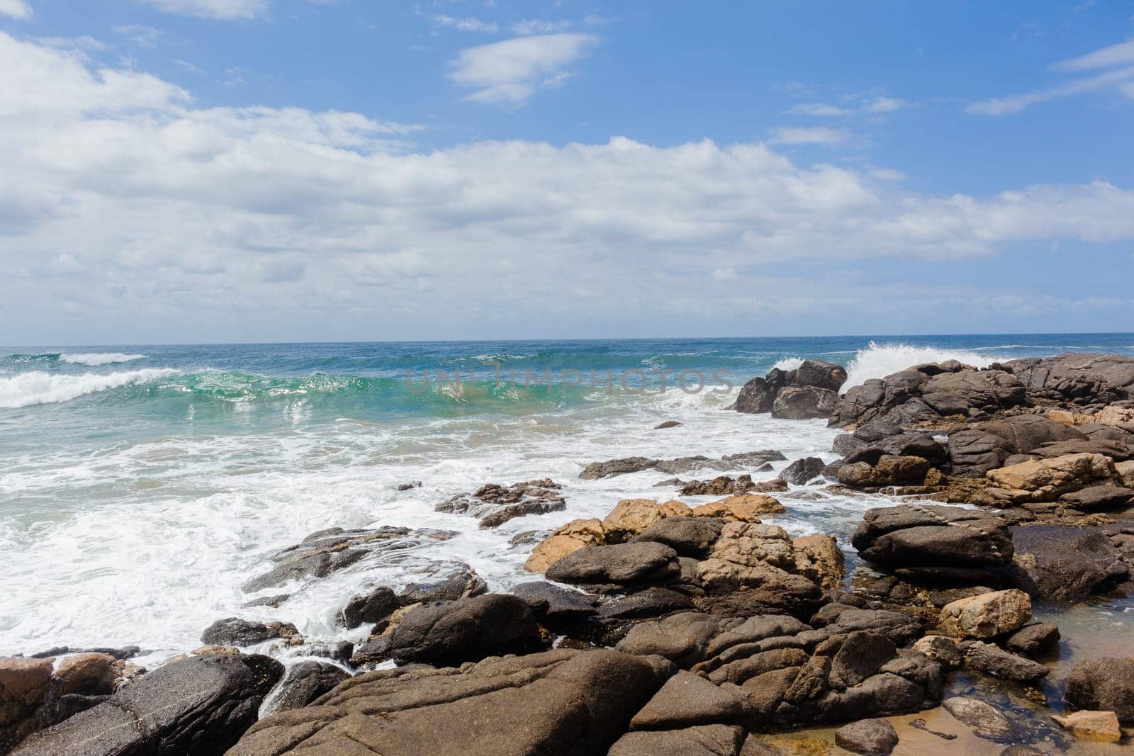 Ocean blue waves crashing along rocky scenic summer coastline landscape.