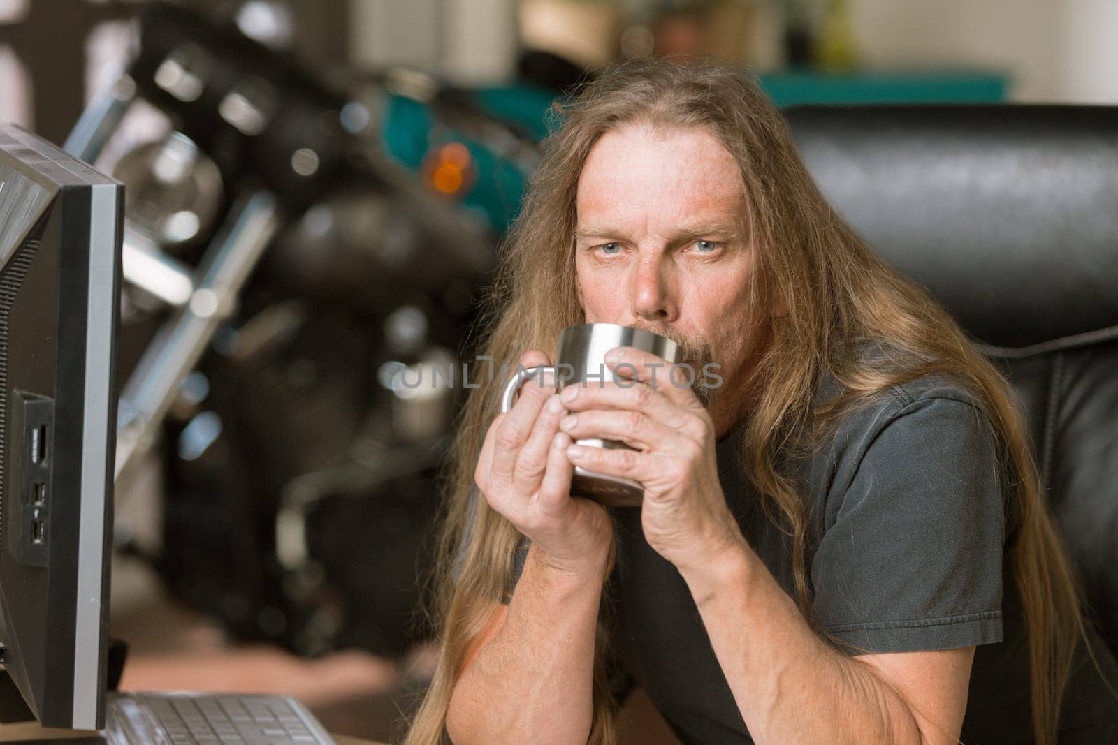 Sleepy man at his desk with a coffee and motorcycle in the background