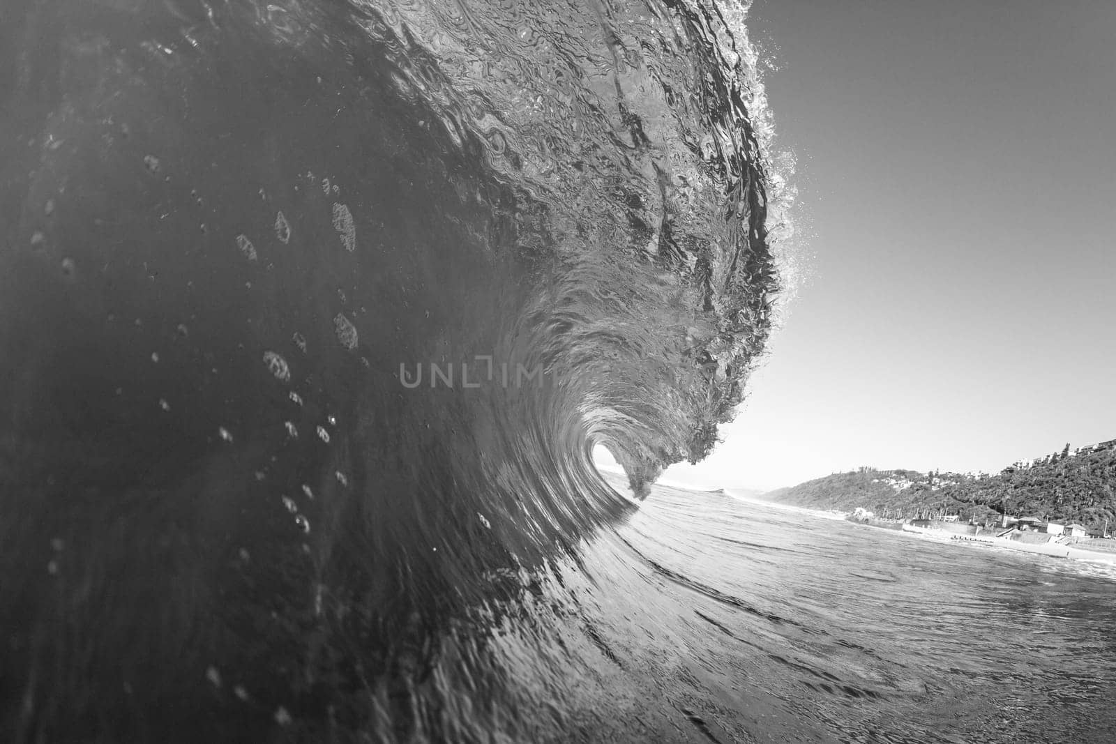 Ocean swimming closeup water photo inside hollow crashing wave black and white contrasts.
