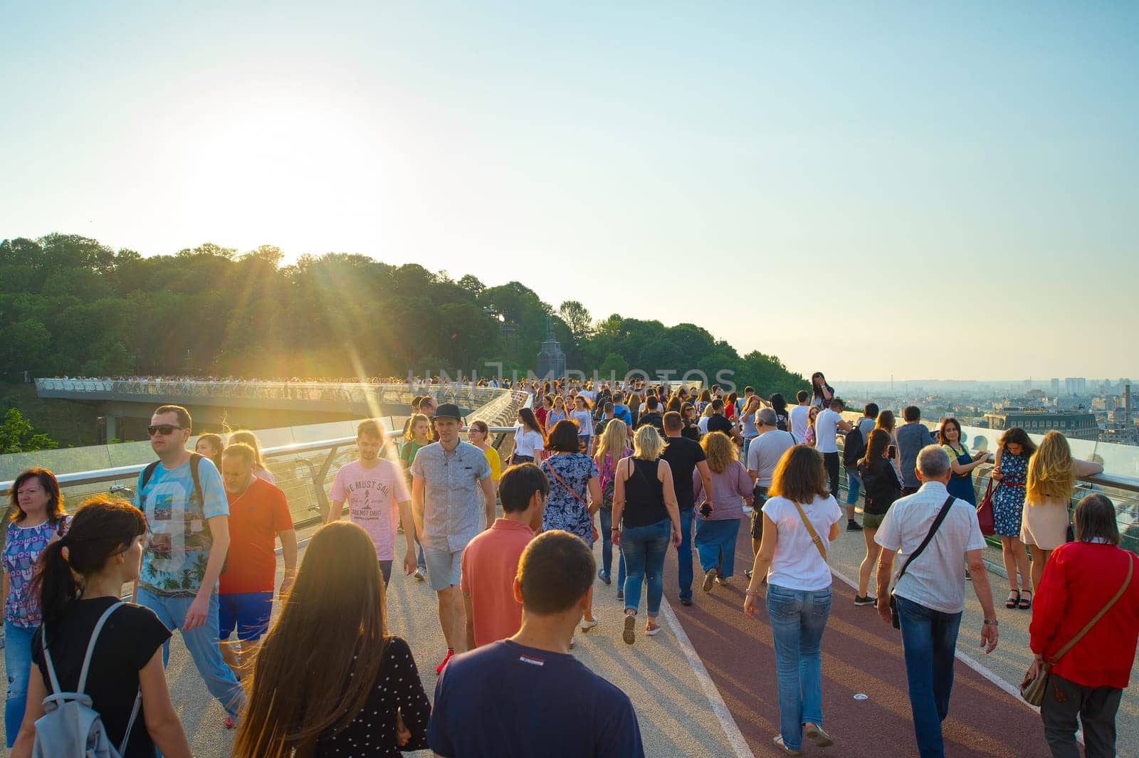 KIEV, UKRAINE - MAY 31, 2019:  Crowd of people at new Pedestrian-Bicycle Bridge at sunset. New Klitschko Pedestrian-Bicycle Bridge one of the most interesting attractions of Kiev