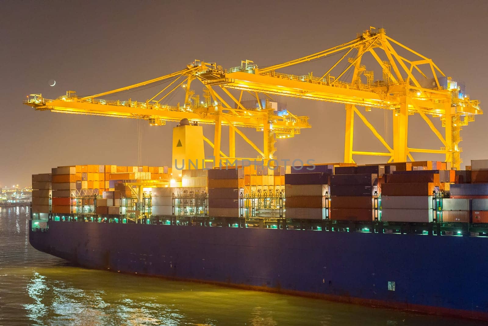 Tanker, cranes and containers at industrial sea port at night. Barcelona, Spain