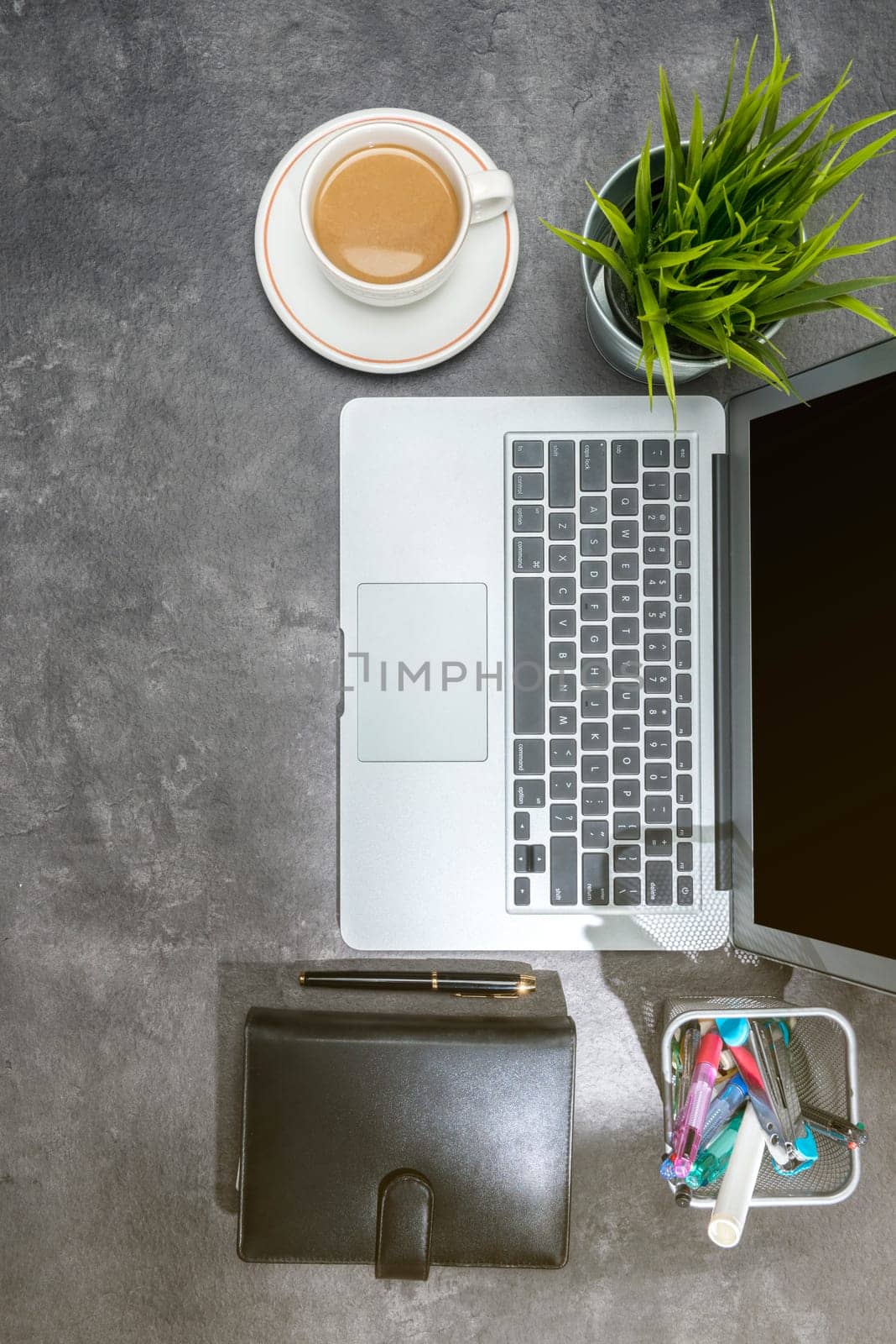 Top view of business desk with laptop, coffee, potted plant, notebook and business accessories on the office