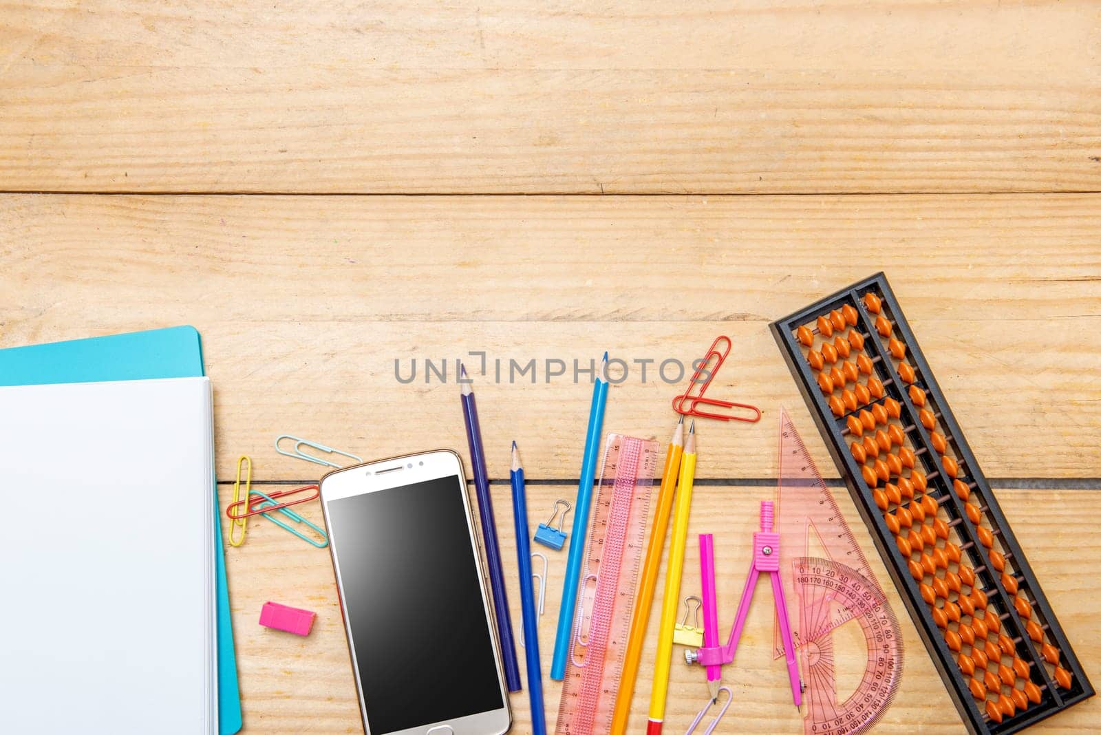 Notebooks and mobile phone with school supplies and stationery on the wooden table. Back to School concept
