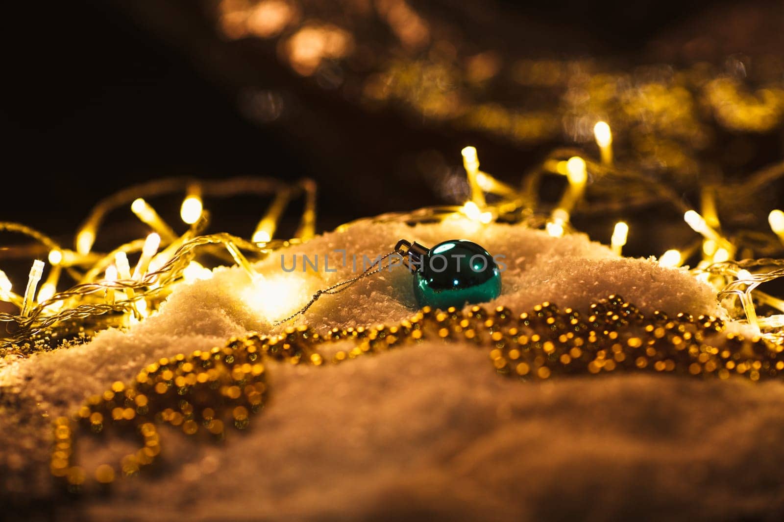blue Christmas ball and luminous garland on the snow.