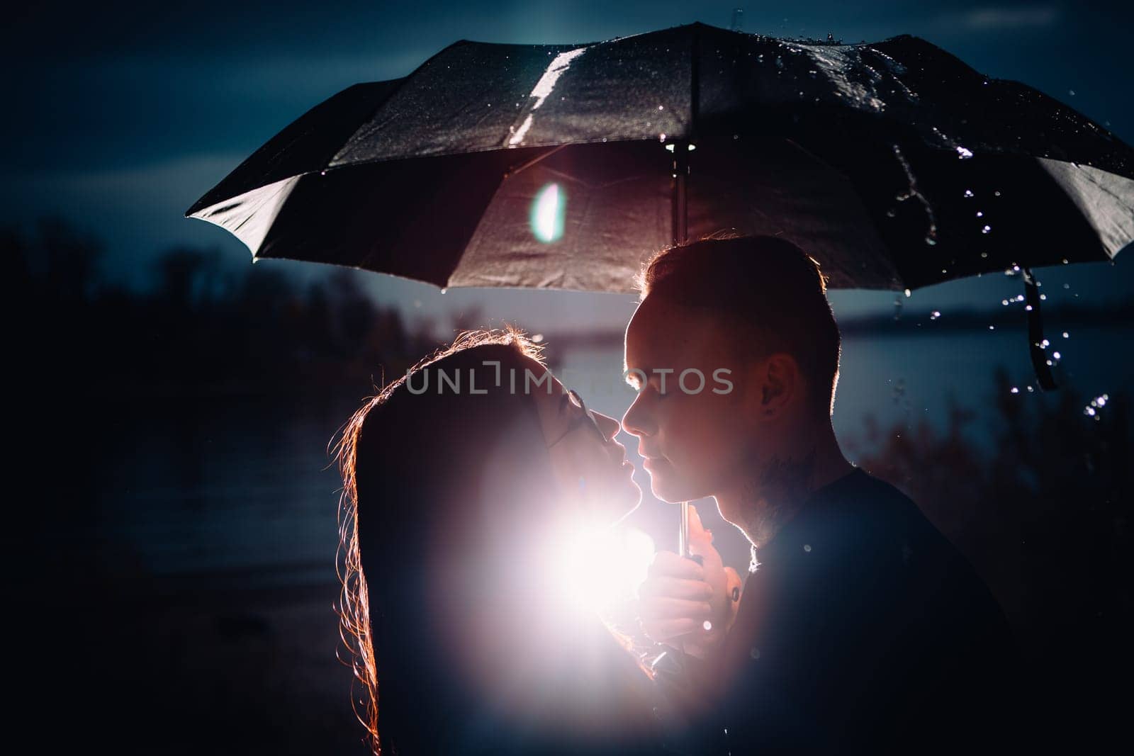young man and woman under an umbrella and rain.