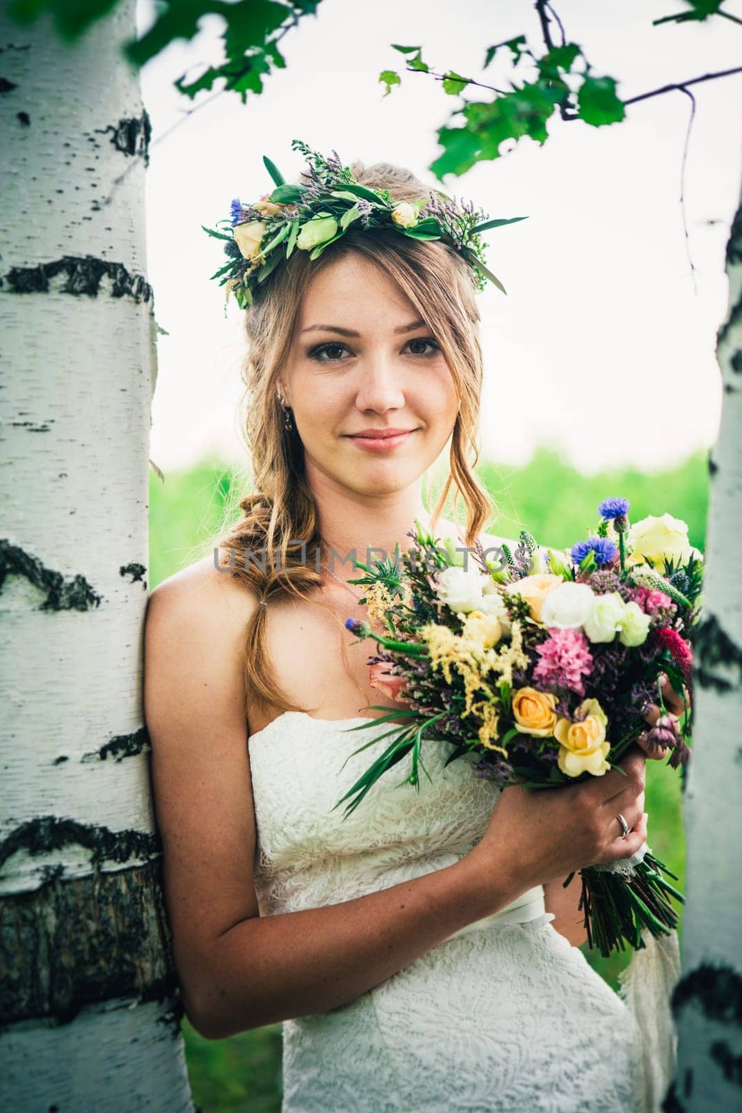 Young bride near birches in the forest.