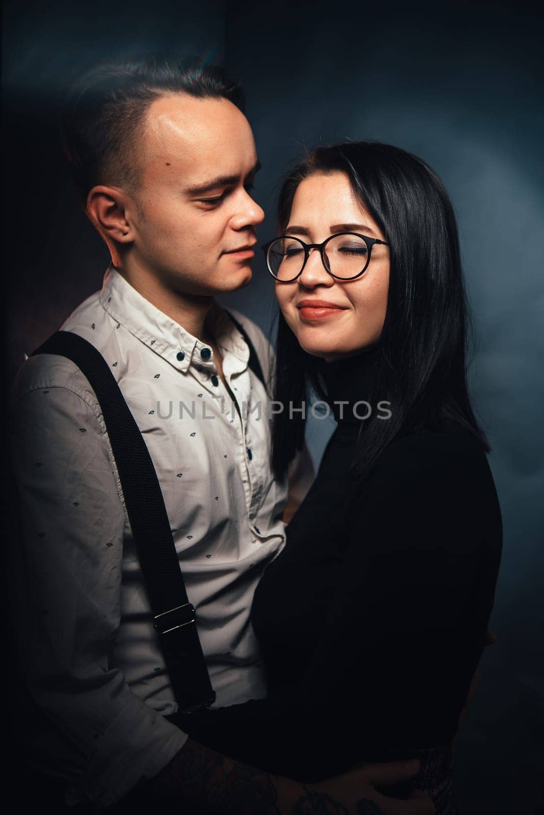 Couple in fashionable clothes on a dark background with smoke.