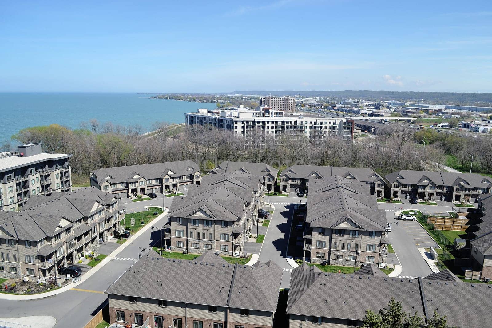 An aria view of some big development with new houses and condo.buildings on the shore of lake Ontario on a sunny spring day.
