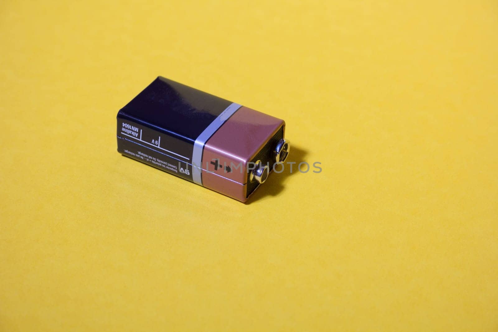 Single alkaline battery on a yellow background