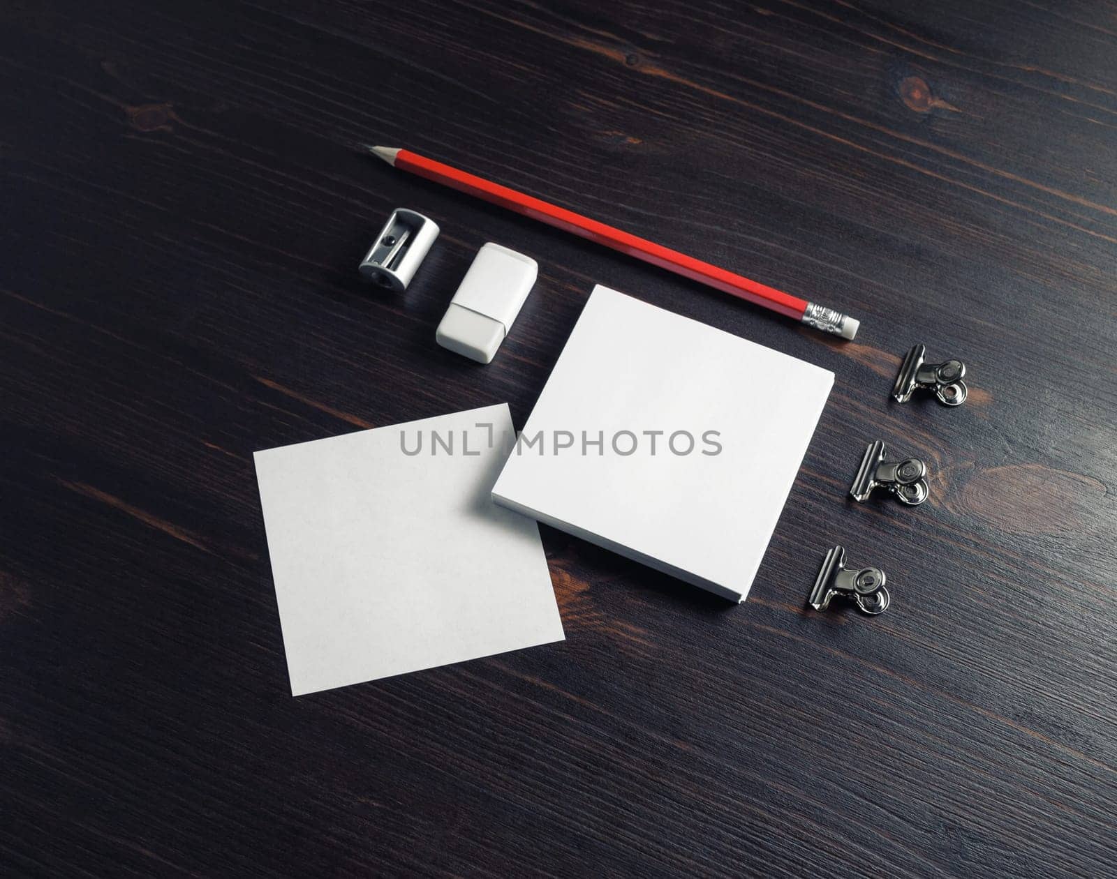 White square notes, pencil, eraser and sharpener on wooden background. Blank stationery template.