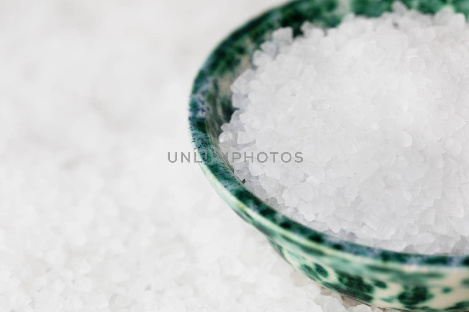 Salt crystals in green bowl on bed of salt.