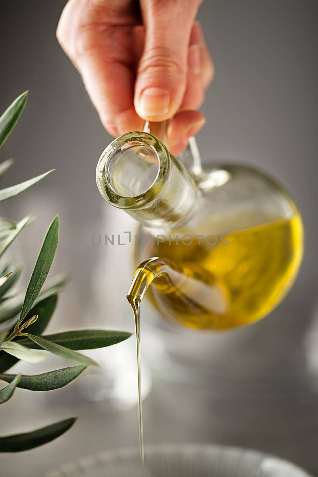 Preparing healthy meal with olive oil. Bottle of Extra virgin oil pouring in to bowl. Healthy food concept.