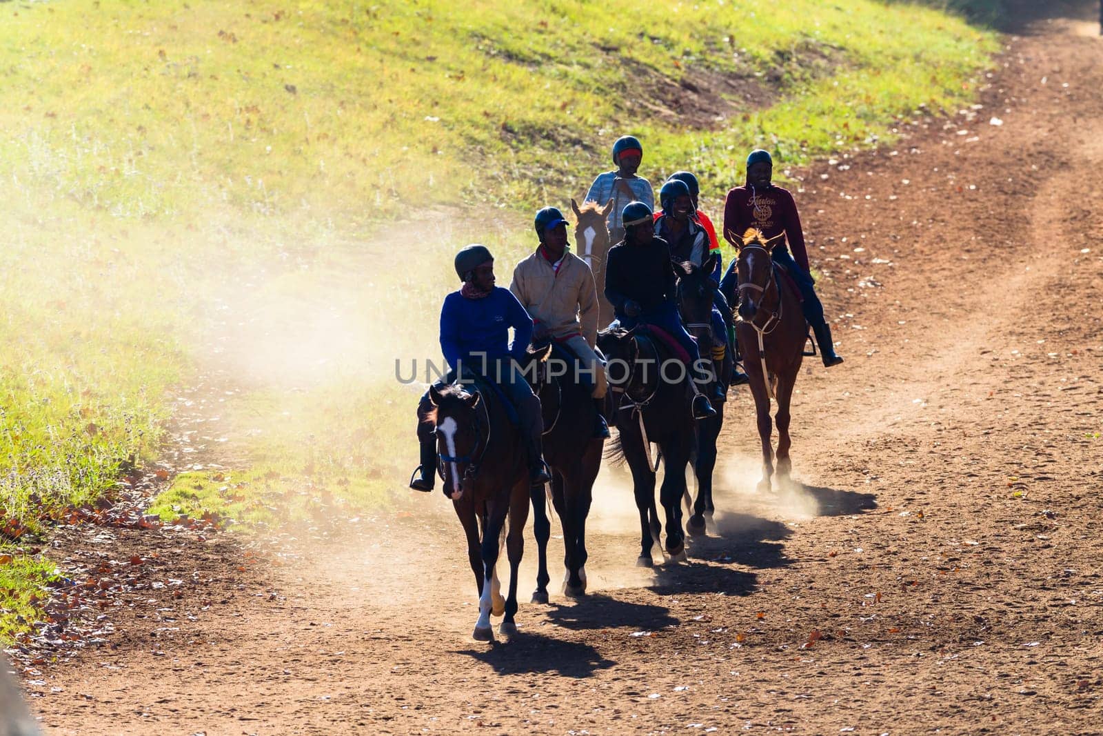 Race horses and riders unidentified silhouetted walking riding going to stables on dirt path after morning training session